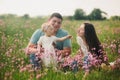 Family enjoying life together in the summer field with wild flowers. Happy young family outdoors. Mother, father are hugging their Royalty Free Stock Photo
