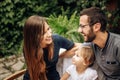 Family enjoying with their daughter in the garden. Pretty blonde little girl in the garden sitting between her young parents. Love