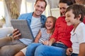 Family entertainment at a touch. smiling parents sitting with their young son and daughter on their living room sofa at