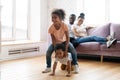 Happy married couple watching their children playing leapfrog on floor Royalty Free Stock Photo