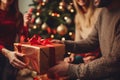A family exchanging beautifully wrapped gifts in front of a festively decorated Christmas tree, capturing the essence of sharing Royalty Free Stock Photo