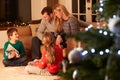 Family Exchanging Gifts By Christmas Tree