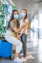 Mother and little girl with medical masks at airport. Protection against Coronavirus and gripp Royalty Free Stock Photo