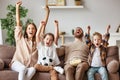 Family of fans watching a football match and celebrating goal on TV at home Royalty Free Stock Photo