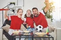 Family of fans watching a football match on TV at home