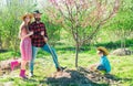 Family Farmers working in tree garden at spring. Father mother and child work in yard with gardener tools.