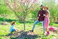 Family Farmers working in tree garden at spring. Father mother and child work in yard with gardener tools.