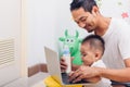 Family father dad eating feeding bottle milk baby boy son drinking and working on laptop Royalty Free Stock Photo