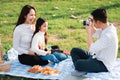 Family father, mother and child having fun and enjoying outdoor together sitting on the grass party with shooting photos Royalty Free Stock Photo