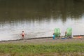 Family: father, mother and son are resting on beach chairs on the shore by the pond. Family holiday on the water. Beach of sand an