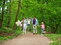 Family father and mother with two kids walking in summer green city park on picnic, happy holidays parents and children on nature