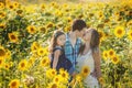 Family father mother and 5 years old daughter standing in sunflowers field. Love, togetherness, trust, family summer vacation.