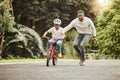 Family, father teaching child cycling in park with bicycle and helmet for safety, learning and help. Support, motivation