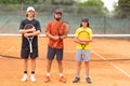 A family of father and two brothers stand on a tennis court holding rackets Royalty Free Stock Photo