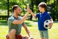 Father giving five to son with soccer ball at park Royalty Free Stock Photo