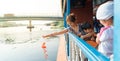 Family are feeding fish on a river boat, Bangkok.