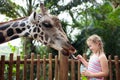 Family feeding giraffe in zoo. Children feed giraffes in tropical safari park during summer vacation. Kids watch animals. Little Royalty Free Stock Photo