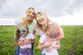 Family, festival of holi and holidays concept - Close up portrait of mothers and daughters covered in paint