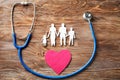 Family figure, heart and stethoscope on wooden background. Health care concept