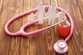 Family figure, red heart and stethoscope on wooden background. Health care concept Royalty Free Stock Photo