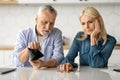 Family Financial Problems. Upset Senior Couple Counting Remaining Coins In Kitchen Royalty Free Stock Photo