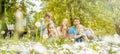 Family of five sitting on a meadow blowing dandelion flowers Royalty Free Stock Photo