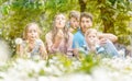 Family of five sitting on a meadow blowing dandelion flowers Royalty Free Stock Photo