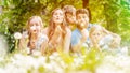 Family of five sitting on a meadow blowing dandelion flowers Royalty Free Stock Photo