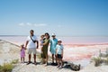 Family with four kids against red salt lake in Saline Margherita di Savoia of Italy