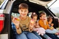 Family of four kids eat apples at vehicle interior. Children sitting in trunk. Traveling by car in the mountains, atmosphere Royalty Free Stock Photo