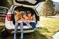 Family of four kids at vehicle interior. Children sitting in trunk. Traveling by car in the mountains, atmosphere concept Royalty Free Stock Photo