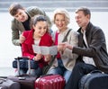 Family of four with luggage checking direction in map Royalty Free Stock Photo