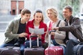 Family of four with luggage checking direction in map Royalty Free Stock Photo