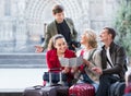 Family of four with luggage checking direction in map Royalty Free Stock Photo