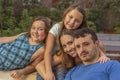 A family of four, mom, dad, and two young sisters relax, holding each other while looking at the camera Royalty Free Stock Photo