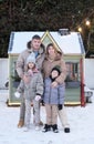 A family of four poses in the yard in winter against the backdrop of an orphanage