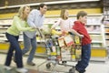 Family Of Four Running With Full Shopping Trolley