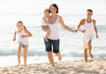 Family of four running on sandy beach on sunny weather