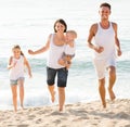 Family of four running on sandy beach on sunny weather Royalty Free Stock Photo