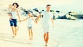 Family of four running on sandy beach on sunny weather Royalty Free Stock Photo