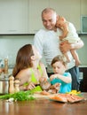 Family of four together in the kitchen prepares seafood