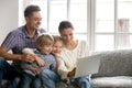 Family of four using laptop sitting on sofa at home Royalty Free Stock Photo