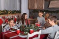 A family of fours at a festive New Year`s table talking to have fun, the son pours tea from the kettle