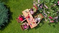 Family and friends eating together outdoors on summer garden party. Aerial view of table with food and drinks from above