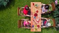 Family and friends eating together outdoors on summer garden party. Aerial view of table with food and drinks from above