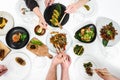Family, friends gathering dinner. Hands of people eating roasted duck, dumplings, spring rolls, wok noodles, salads, vegetables,
