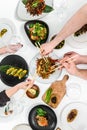 Family, friends gathering dinner. Hands of people eating roasted duck, dumplings, spring rolls, wok noodles, salads, vegetables,