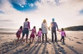 Family and friends group standing on the beach holding hands