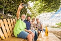 Family and friends have fun all together in outdoor leisure activity sit down on a recycled wooden bench and taking picture selfie
