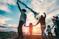 Family friends having fun with fireworks at sunset on the beach - Adult people having fun with their children for holidays event Royalty Free Stock Photo